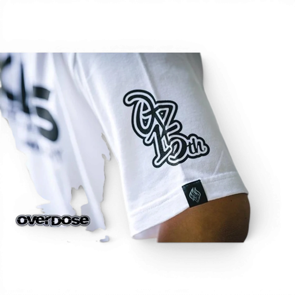 T-shirt Overdose 15th Anniversary en coton avec logo, porté, en gris avec design célébrant l'anniversaire.
